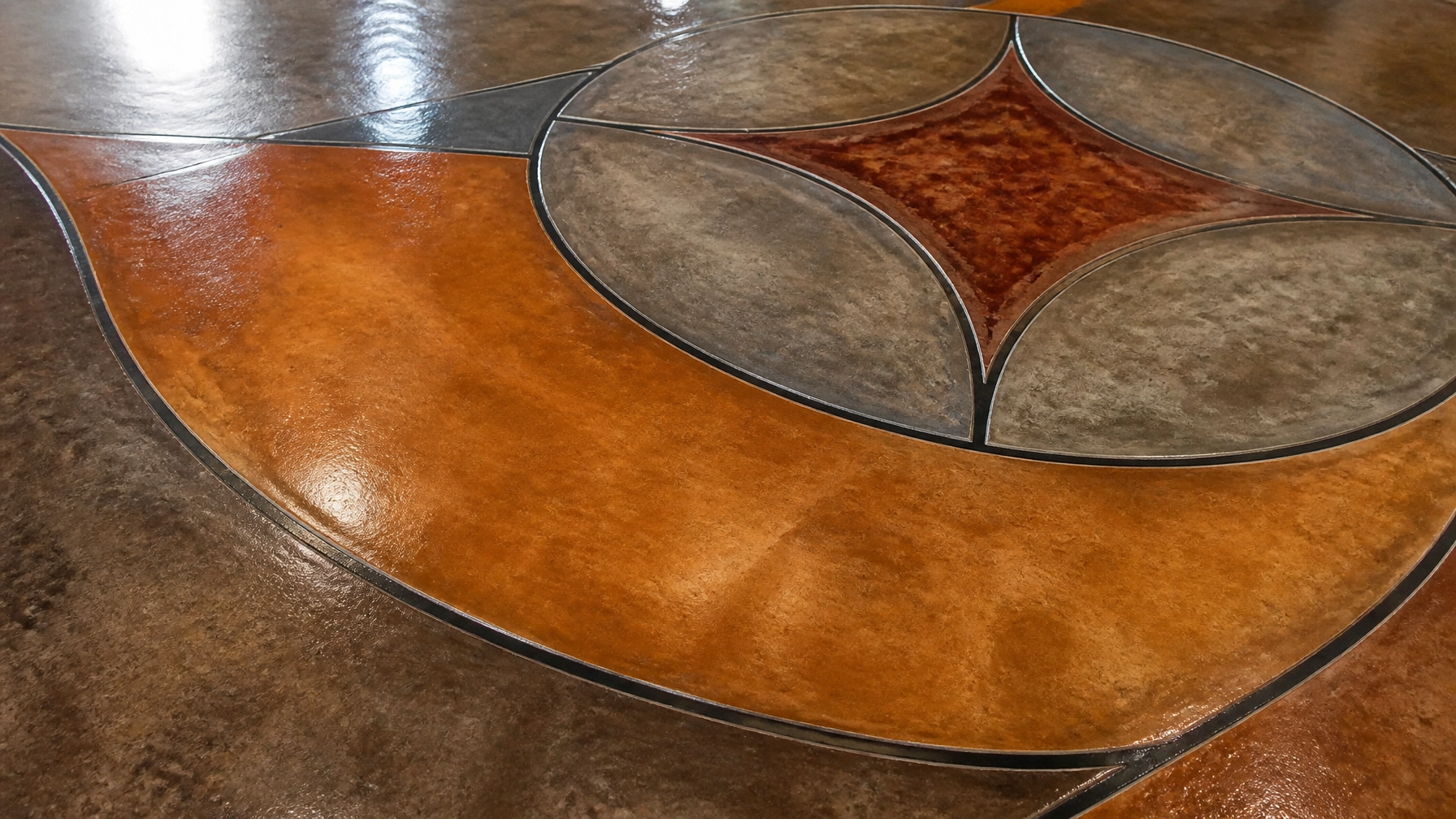 Close-up detail of a sealed decorative stained concrete floor showing protective coating and deep color penetration