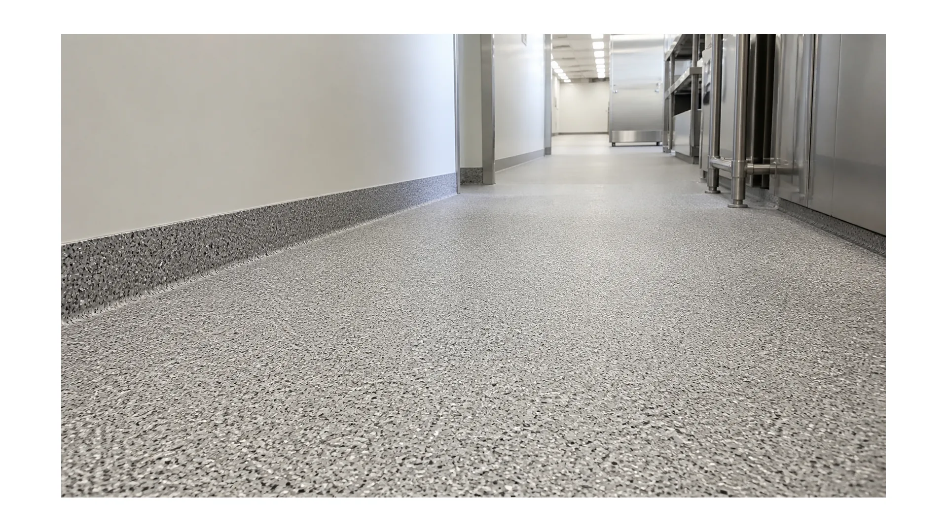 Broadcast resinous flooring with decorative aggregate and cove base in a commercial corridor
