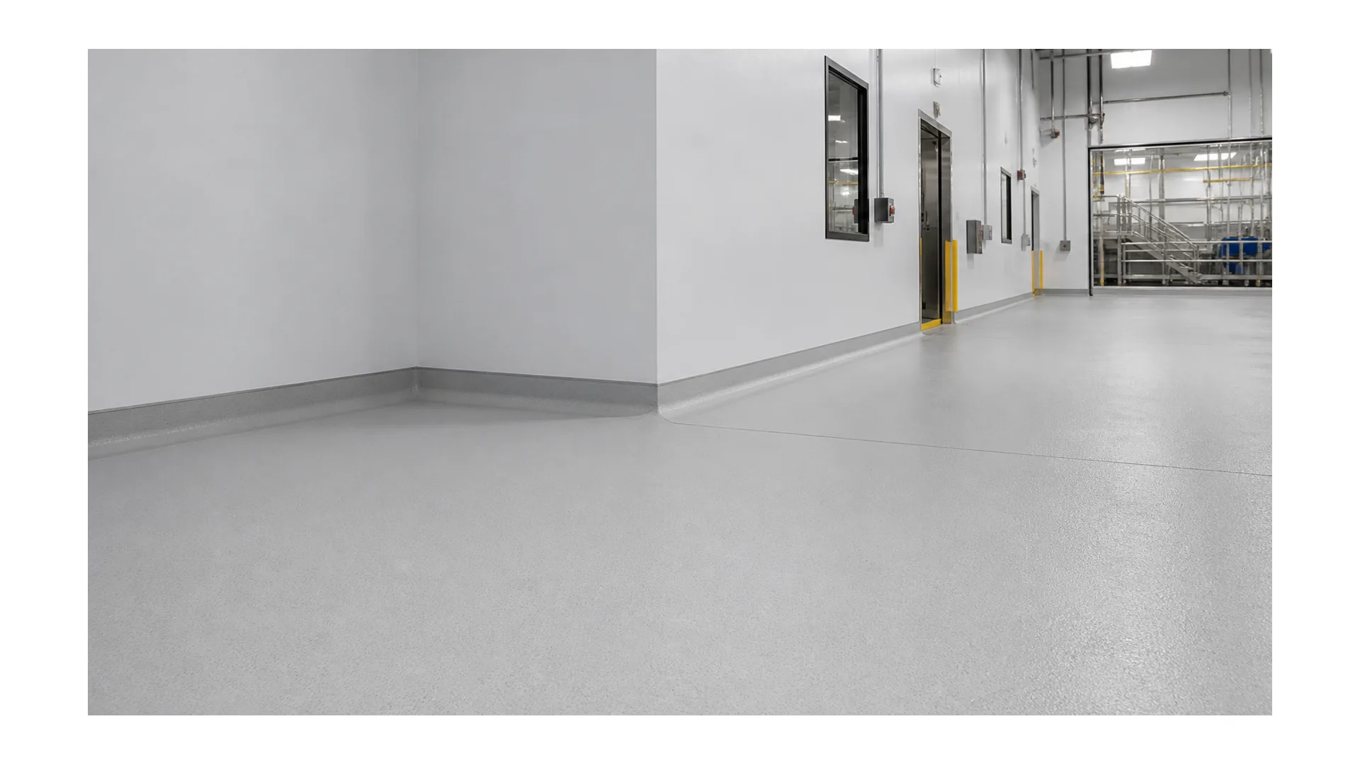 Seamless resinous flooring with cove base in a clean light industrial corridor