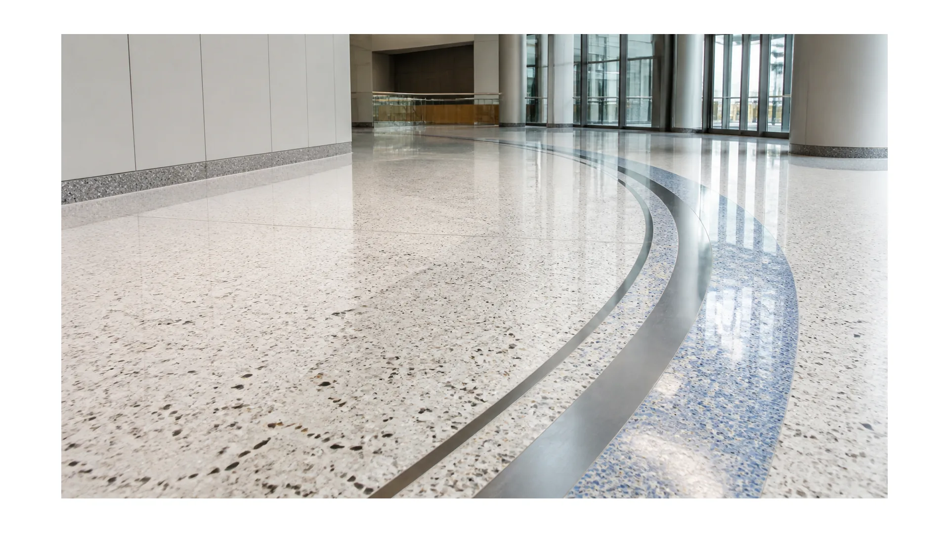 Finished terrazzo flooring with aggregate chips and metal divider strips in a bright lobby